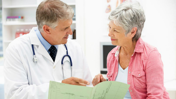 A male physician speaking to a female patient as they point at her chart