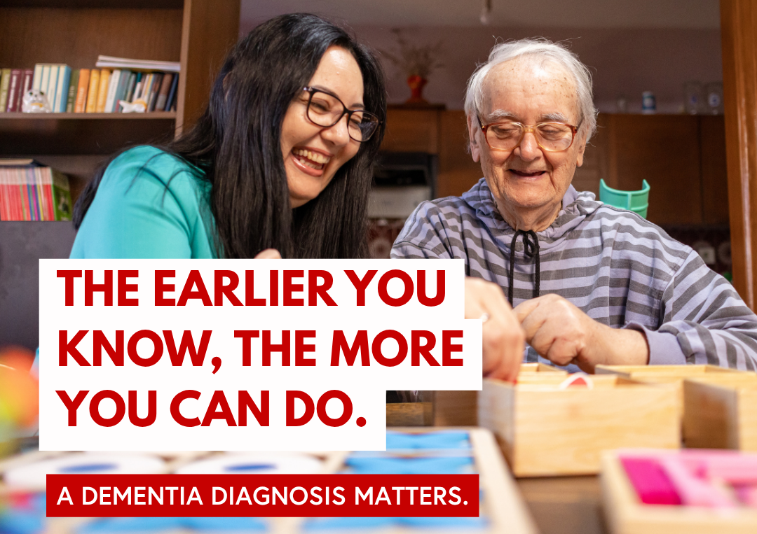 Two people sit at a table indoors, working with wooden puzzle and activity boards for World Alzheimer's Month