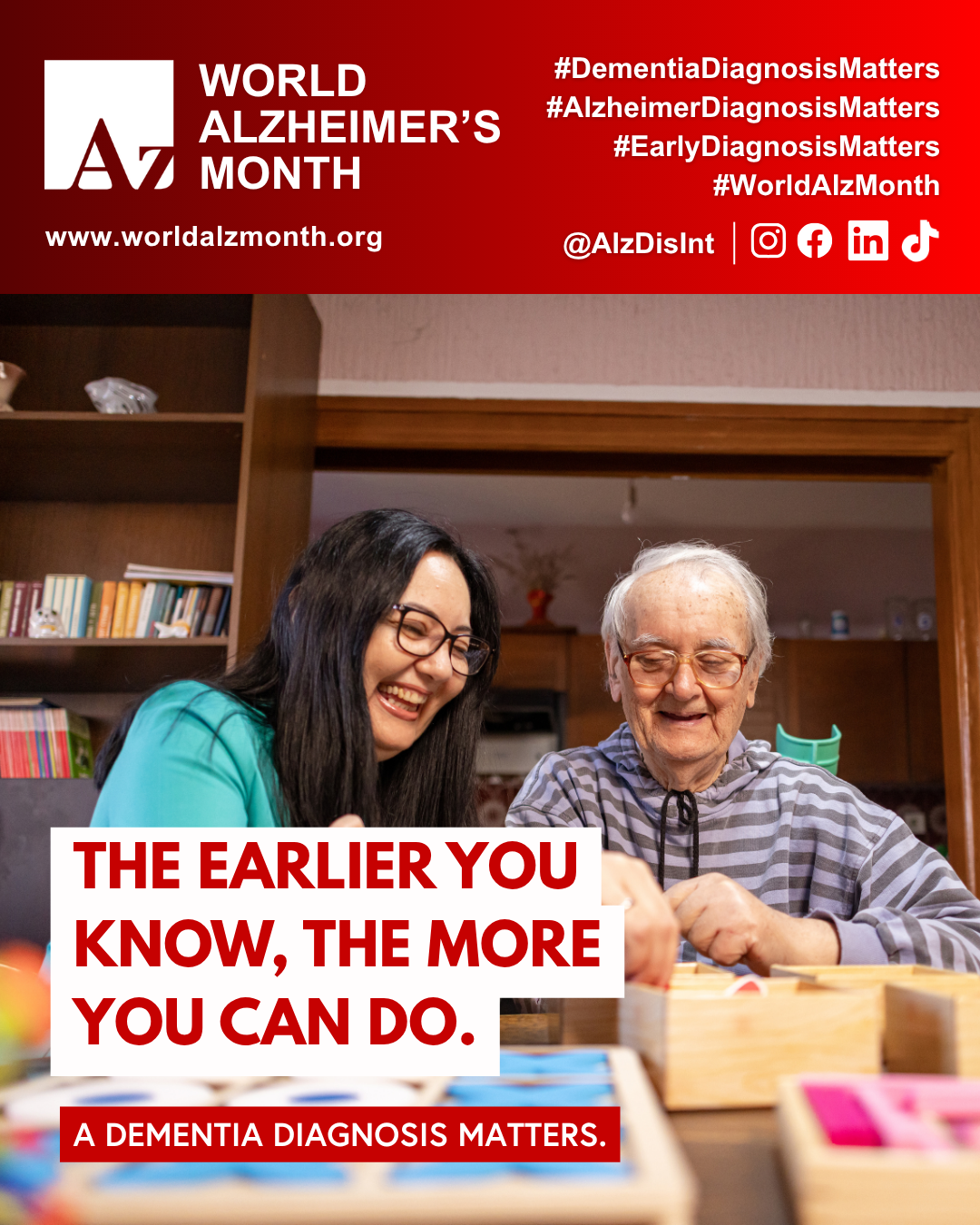 Two people sit at a table indoors, working with wooden puzzle and activity boards for World Alzheimer's Month